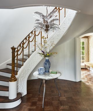 ornate curved staircase with palm tree light