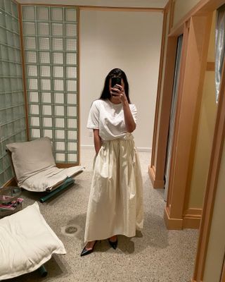 Woman wearing a white T-shirt and full skirt.