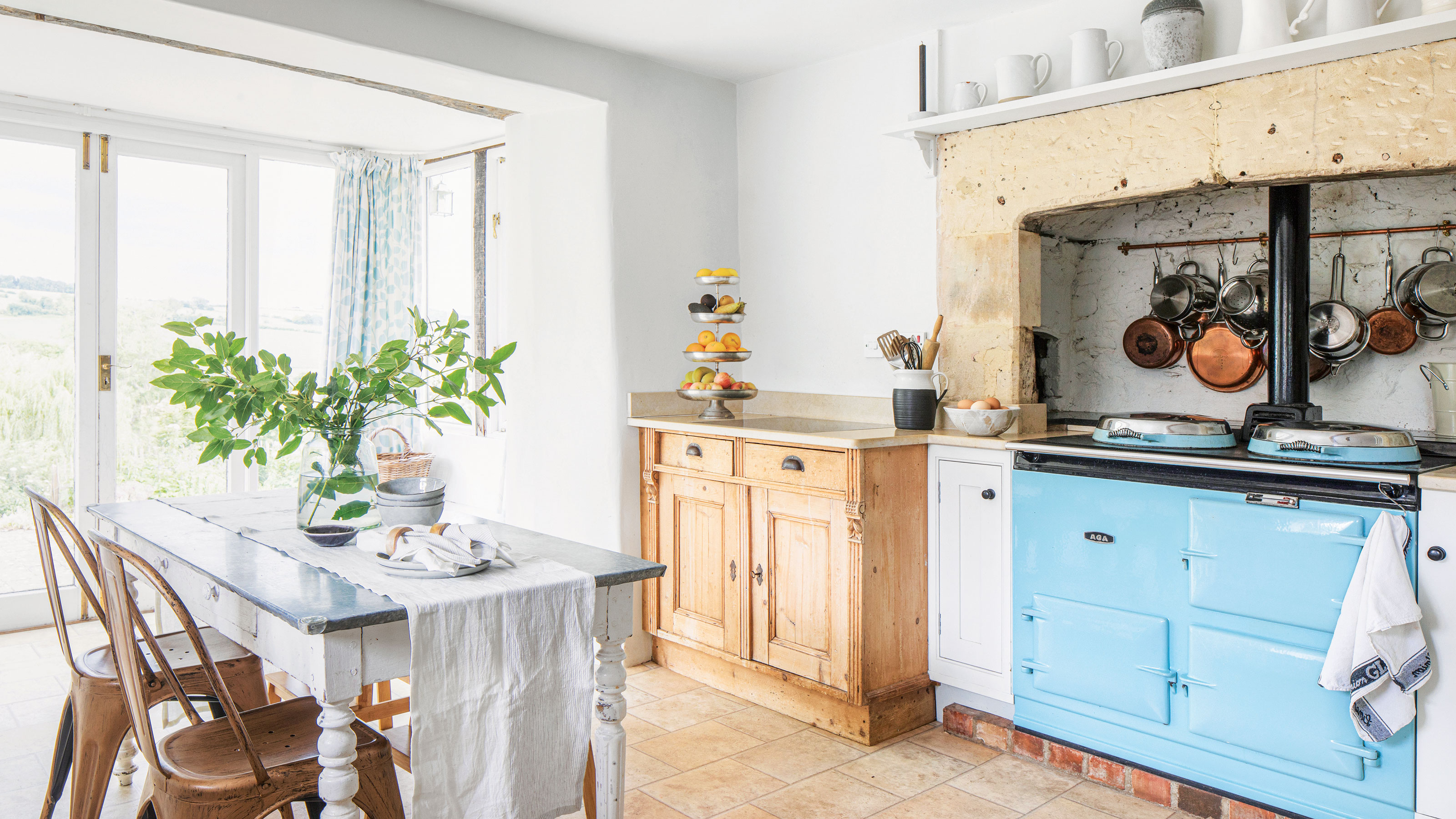 Farmhouse kitchen with blue aga, white farmhouse table and oak cabinetry