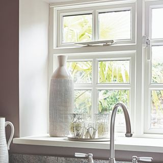 A kitchen window with decoration and sink tap