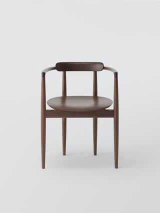 A front-on view of a wood chair with two slim legs at the front and two slim legs at the rear a few inches in from the corners. The base is oval and there is a semi-circular wood back support that runs around to the front legs.