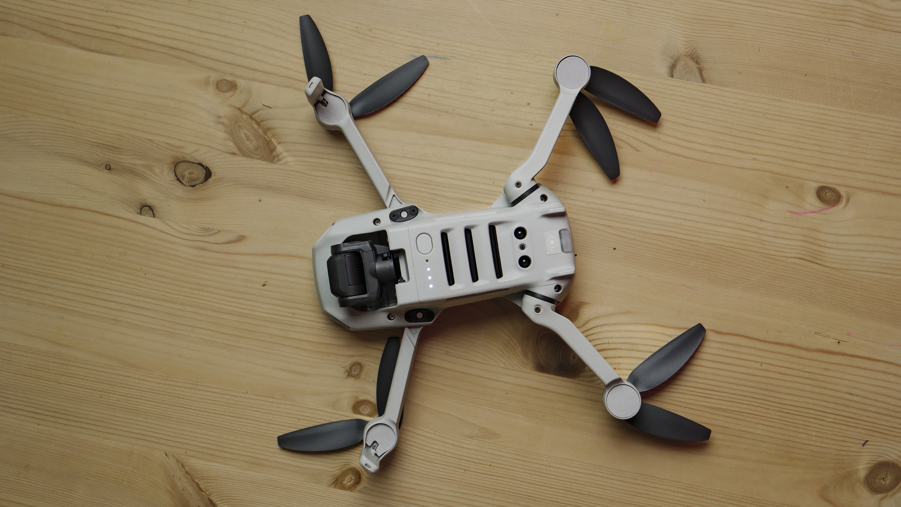 Underside of the DJI Mini 4K beginner drone on a wooden table