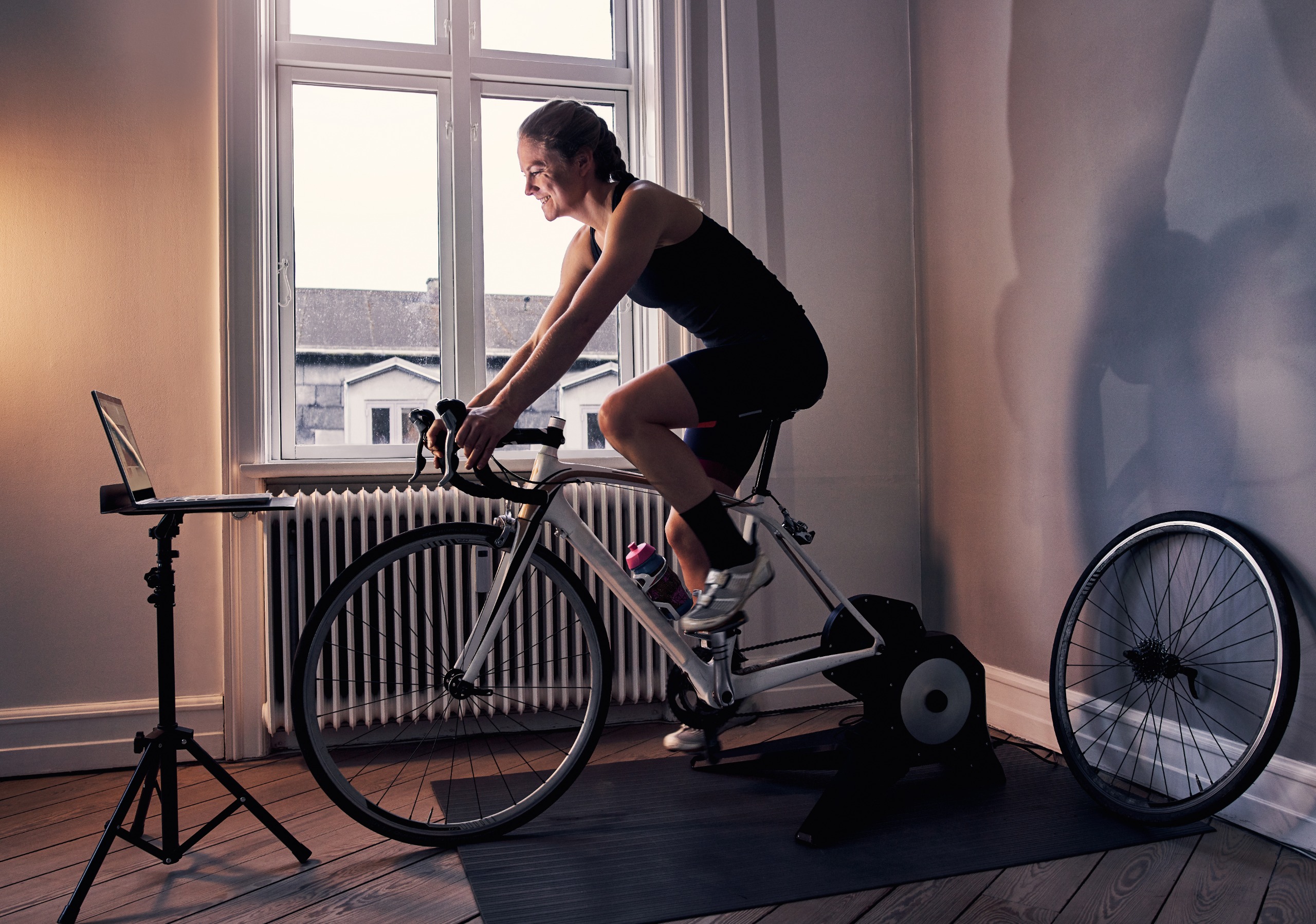 A female cyclist riding a smart trainer in an upstairs room