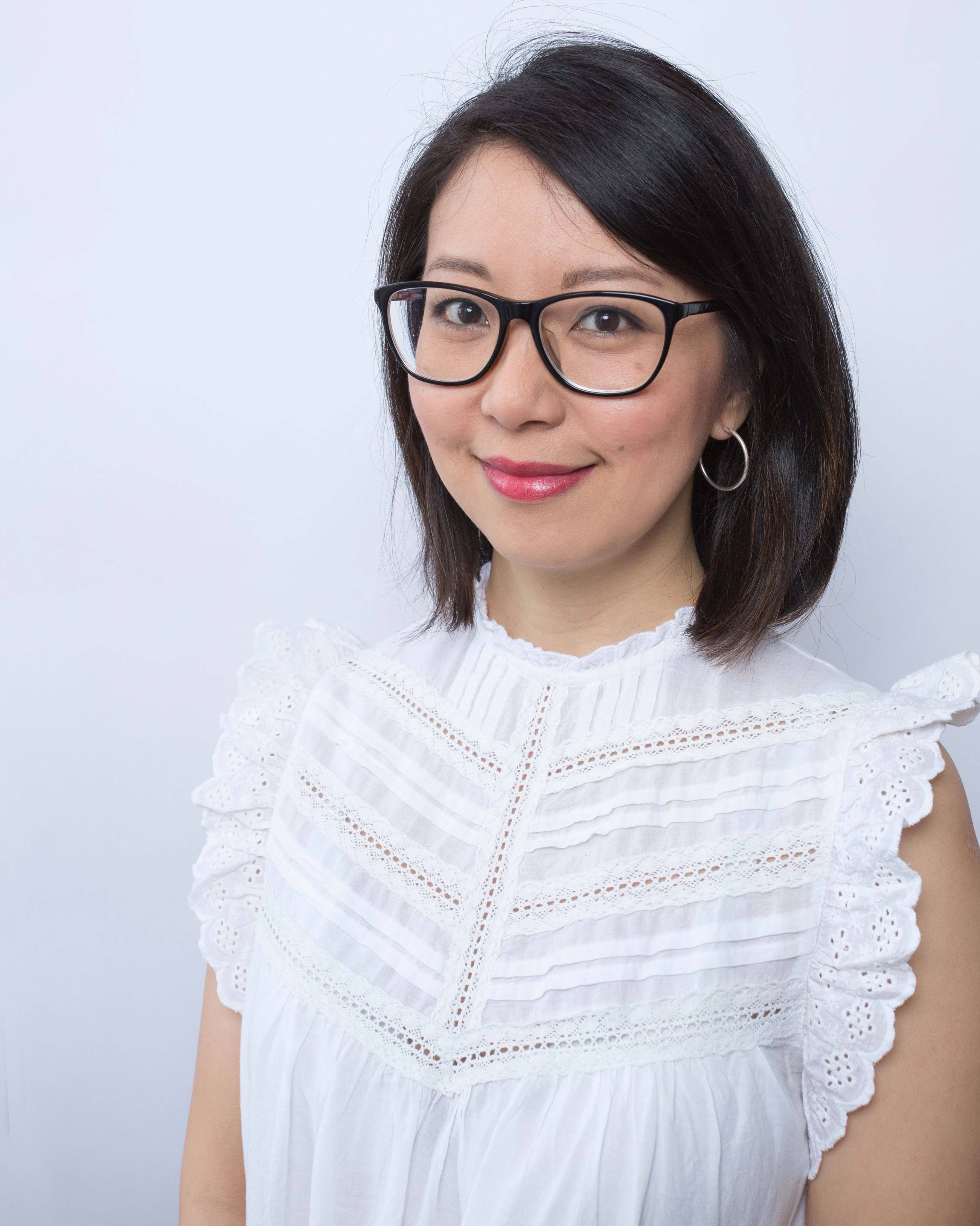 A headshot of a woman with cropped dark brown hair and glasses