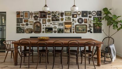 Dining room with long wooden table and bistro chairs and gallery wall with vintage frames and paintings