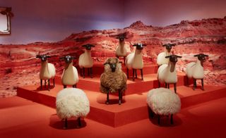 Sculptures of sheep on red layered background and two seating poufs
