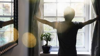 Man opens the curtains on a new day