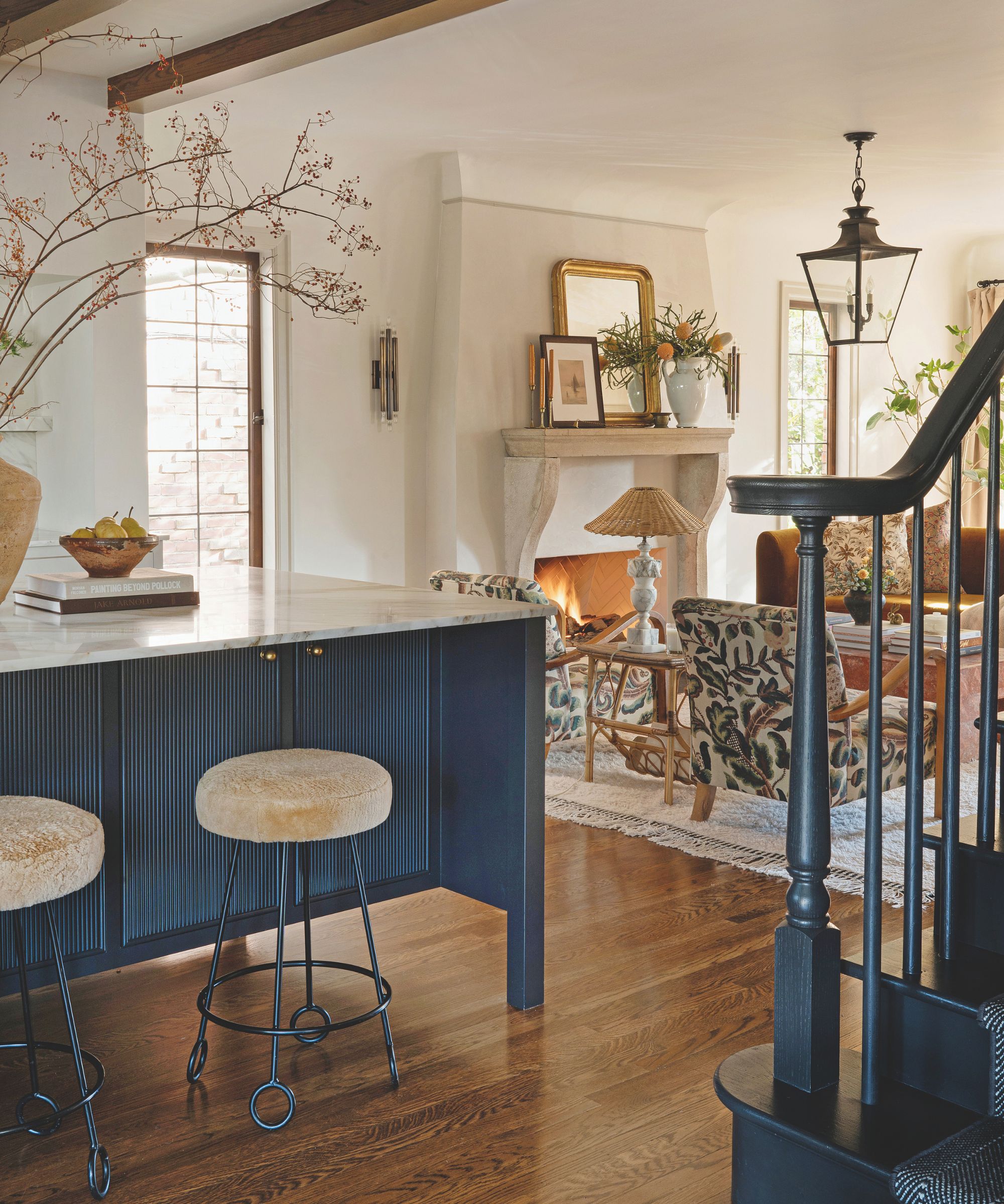 Open plan kitchen with blue island and view through to a living space with a stone mantle and vintage furniture
