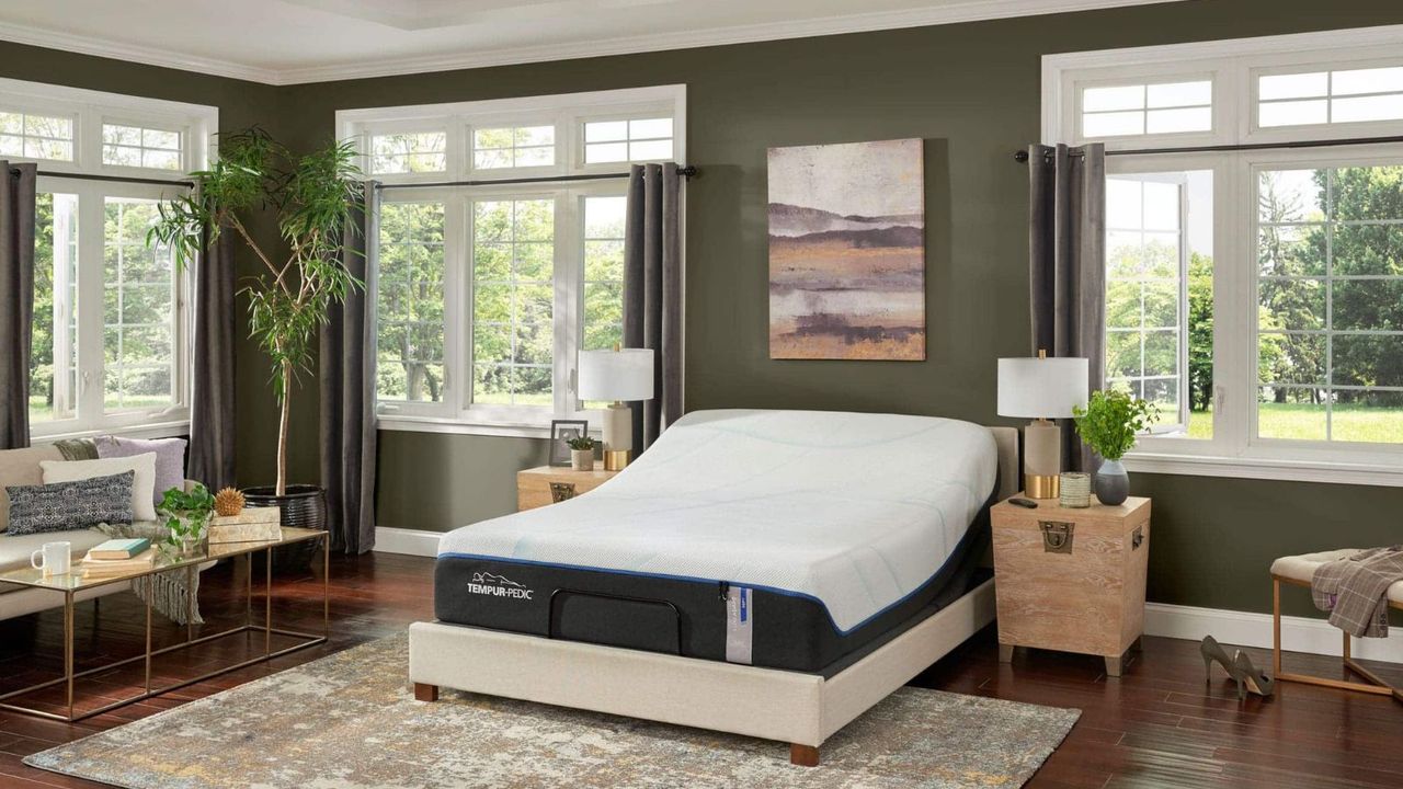 A Tempur-Pedic Luxe Adapt Soft Mattress on a bed against green walls and windows with a garden view.