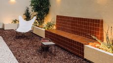 a small woodchip garden with a tiled, rust colored outdoor bench