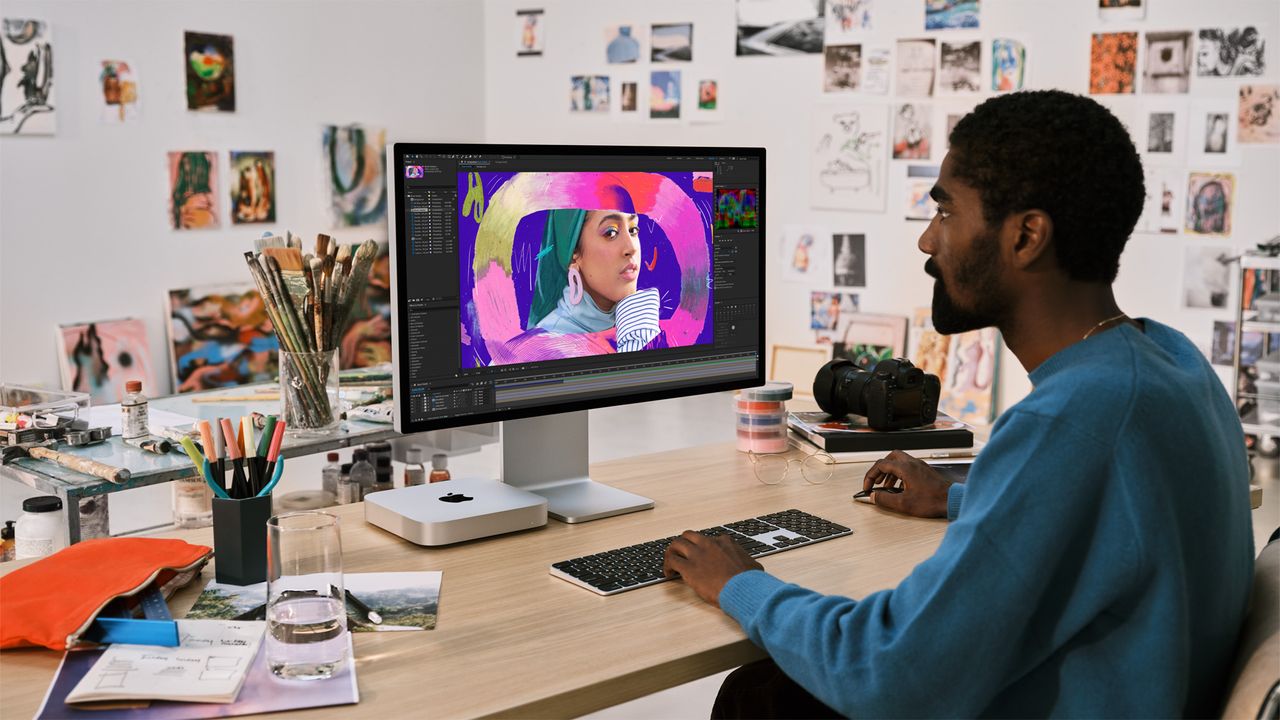 Someone working at a messy desk, with the new Apple Mac mini M2