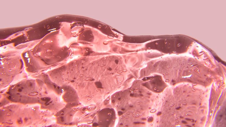 Texture of gel cream. Liquid hyaluronic acid gel on pink background, copy space - stock photo