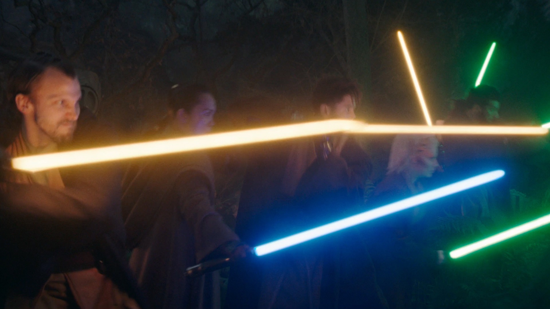 people in robes swing colorful laser swords at one another