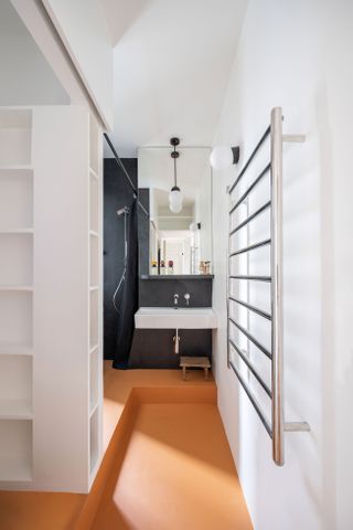 white bathroom with black walls and orange flooring.