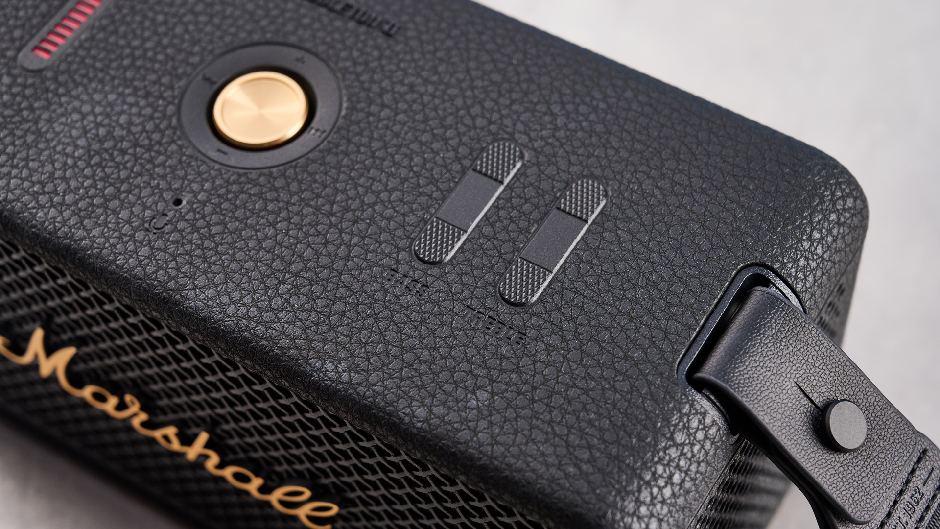 The Marshall Middleton II Bluetooth speaker in Black and Brass, on a stone surface with a blue wall in the background