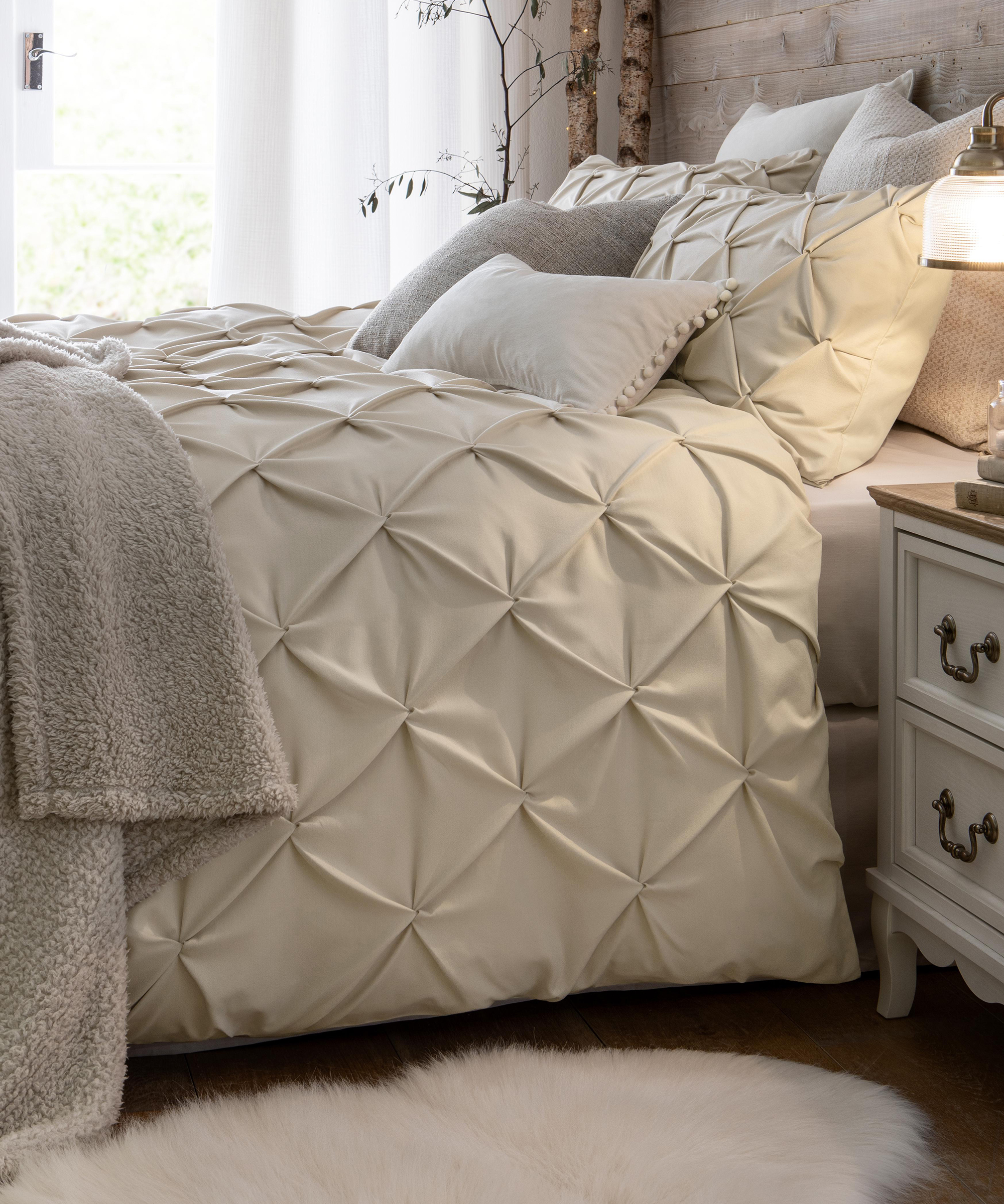 A nordic-inspired white bedroom with tree in corner and quilted bedding with faux wall panelling