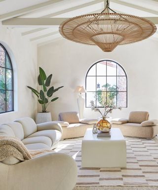 A neutral-toned living room with a large curved couch and tall windows