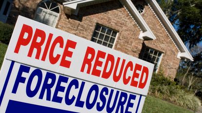 Price reduced and foreclosure sign in front of house for sale