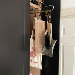Cleaning cupboard with kit stored on hooks from a hanging rail