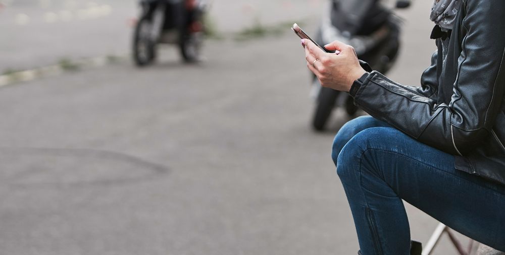 Woman sitting down and using smartphone in profile]