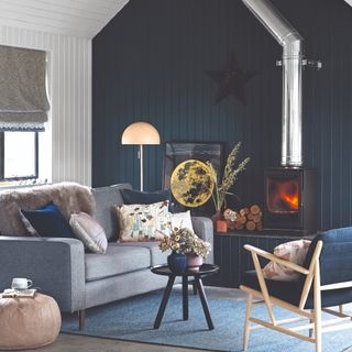A living room with wood-panelled walls and one feature wall painted in navy blue contrasting the other white walls