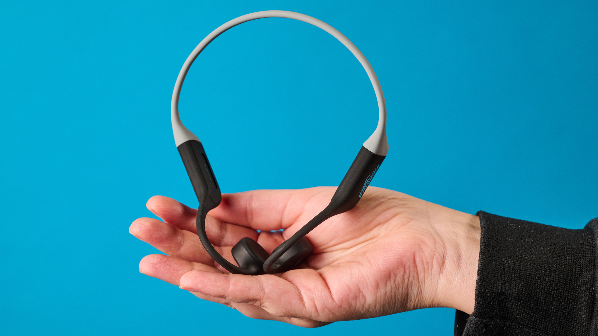the h2o audio tri run bone conduction headphones photographed against a tom's guide blue background
