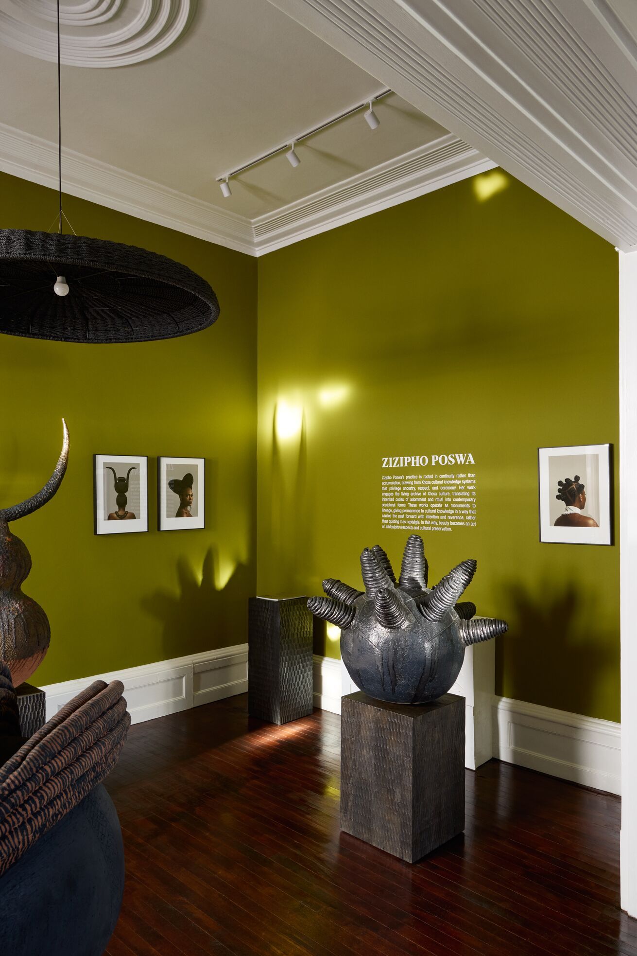 A series of shots capturing a young man dressed in patterned, or color-blocky, clothing, either standing in the sun-lit outdoor areas of a lush hotel, or inside a colorfully decorated suite filled with collectibles, artworks, and textural touches, or the interiors of that very space.