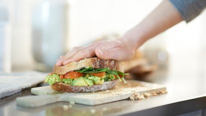 Woman making a vegan sandwich, with smashed avocado and tomato