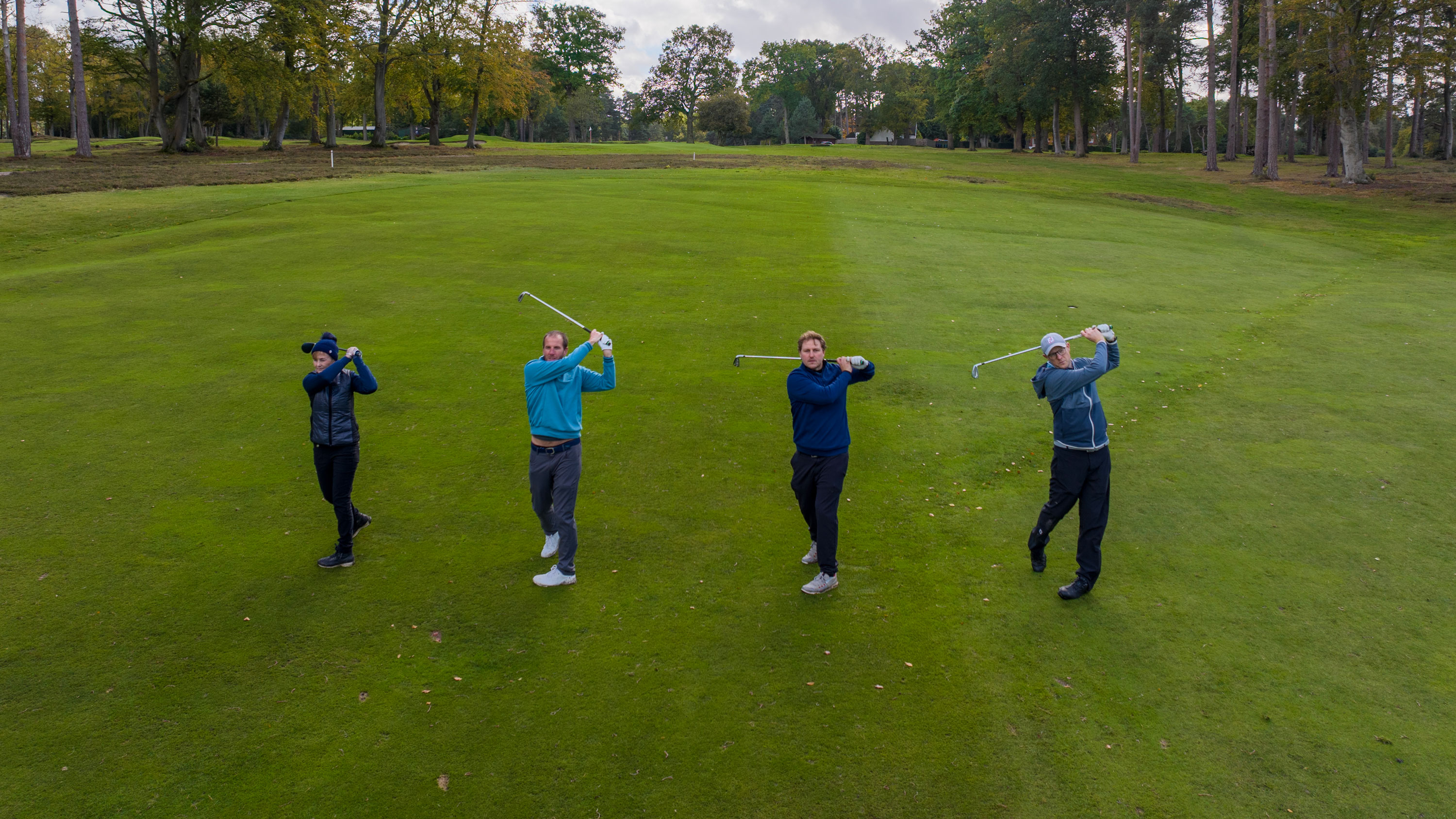 four golfers in the follow-through position