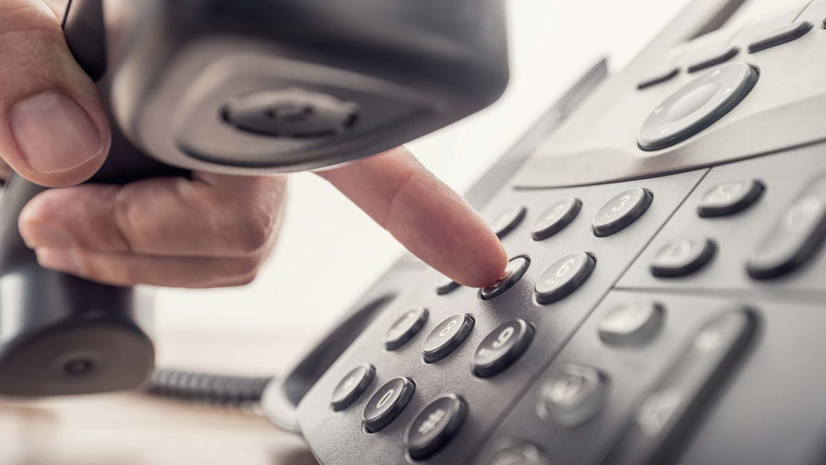 Person dialling an office telephone