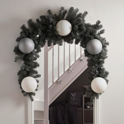 Christmas garland around doorway with large silver and white baubles