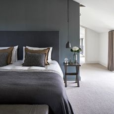 A blue bedroom with a bed dressed in white, grey, and brown bedding