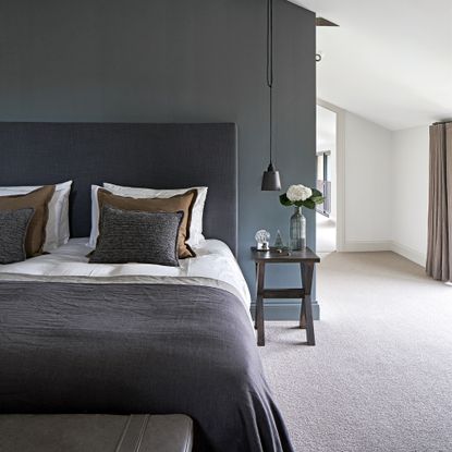 A blue bedroom with a bed dressed in white, grey, and brown bedding