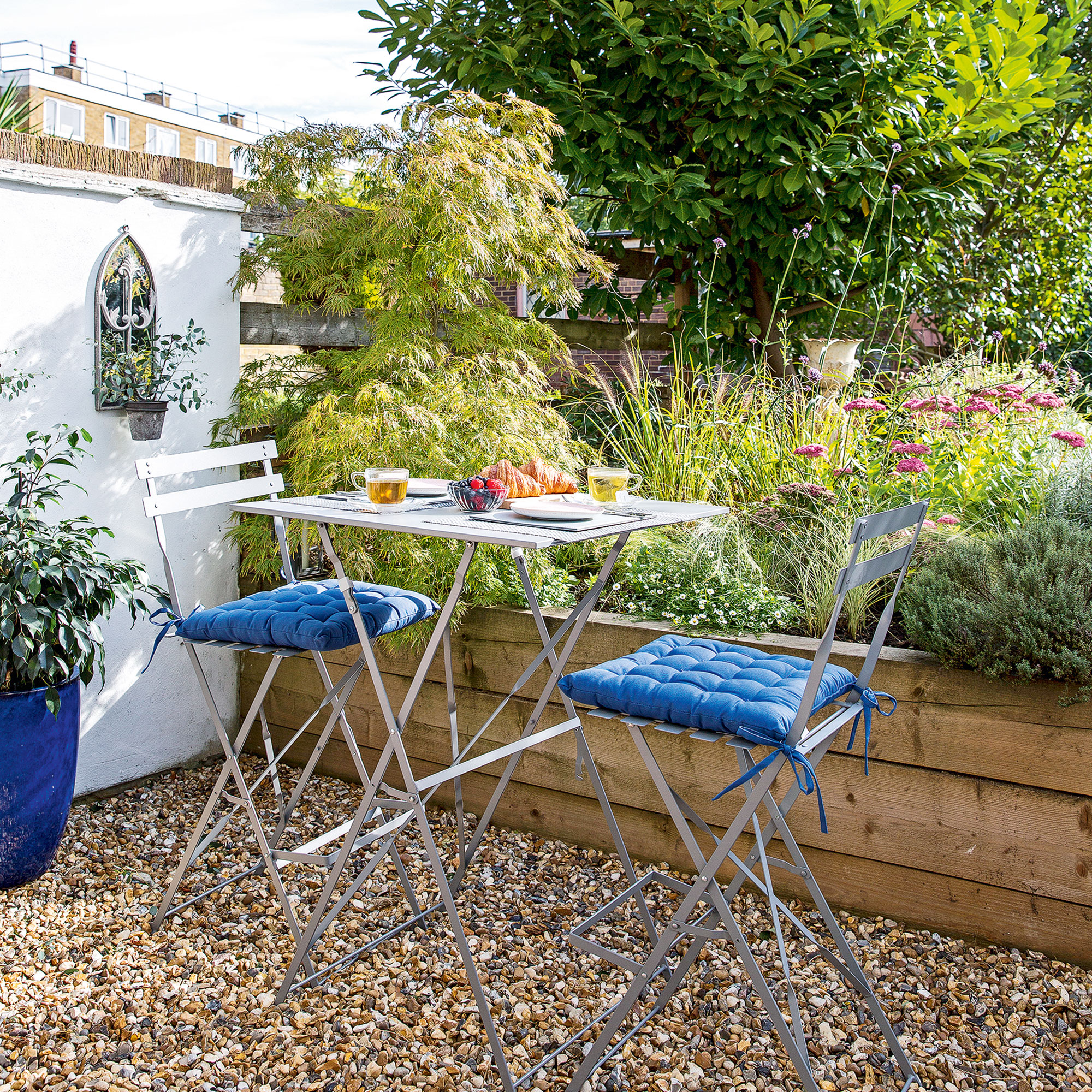 small garden with raised beds and metal bistro set