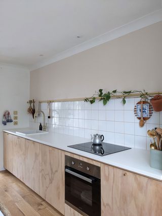 White tiled kitchen with white countertops and wooden custom cupboards