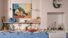 A colorful kitchen with blue cabinets and pink walls