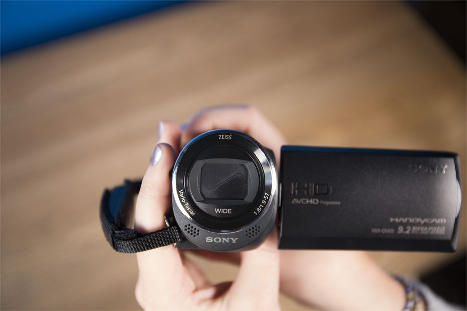 The lens cover on the Sony Handycam HDR-CX405 has to be manually opened with a switch on the side of the camcorder.