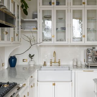 white kitchen with glass fronted cabinets and gold hardware