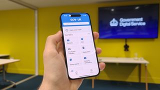 The Gov.uk app open on an iPhone 15 in a brieifing room