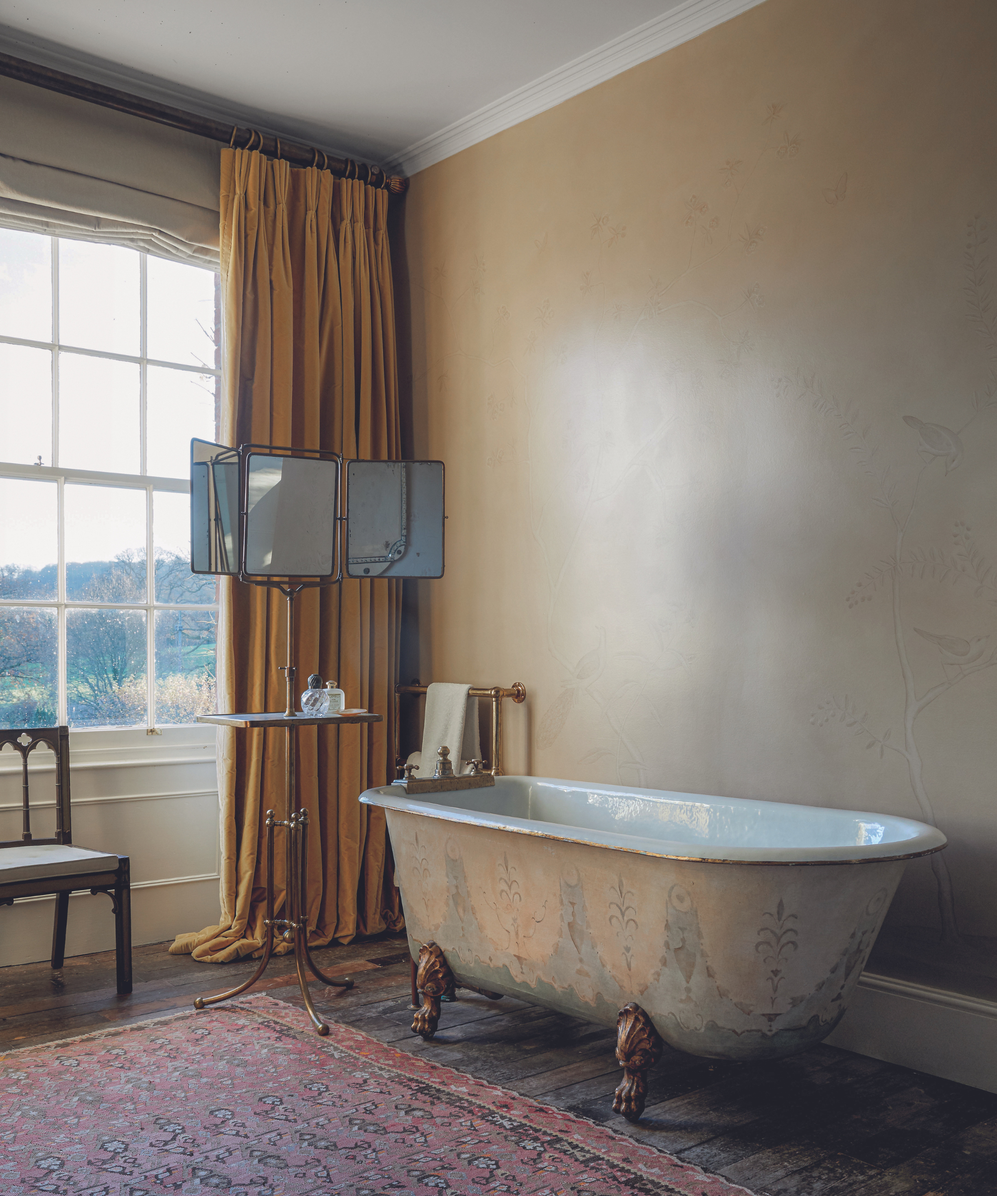 antique bath in victorian style bathroom with draping curtains and rug and gold walls and patterned bath