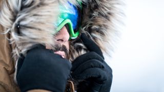 Close up of a man wearing gloves and goggles for skiing