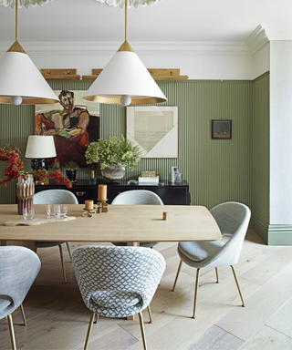 Modern dining room with green paneled walls and white pendant lights