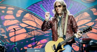 Charlie Starr of Blackberry Smoke performs onstage with a TV Yellow Gibson Les Paul Junior. He wears a brown leather jacket and dark sunglasses.