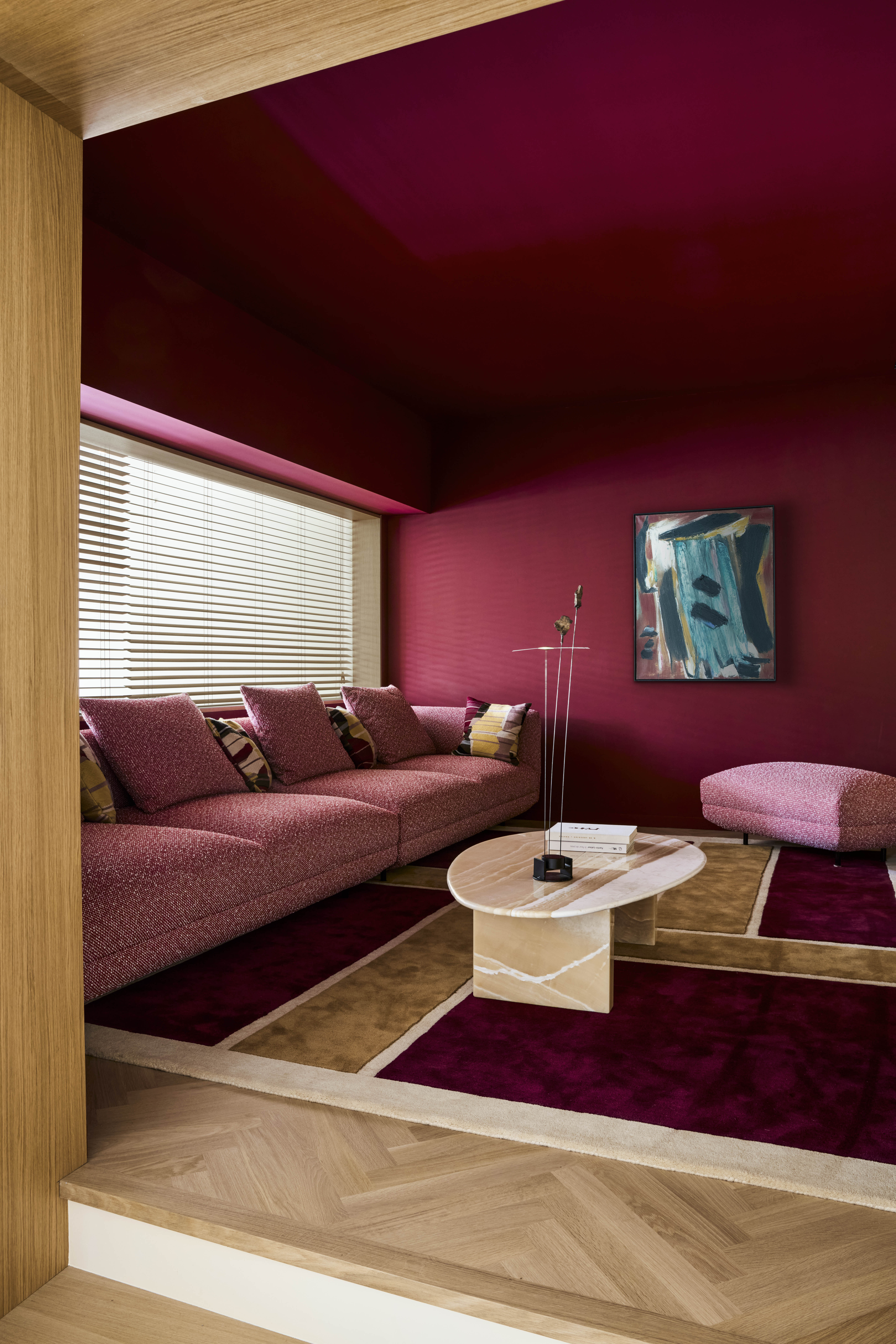 A living room painted in deep red tones, with pink sofas