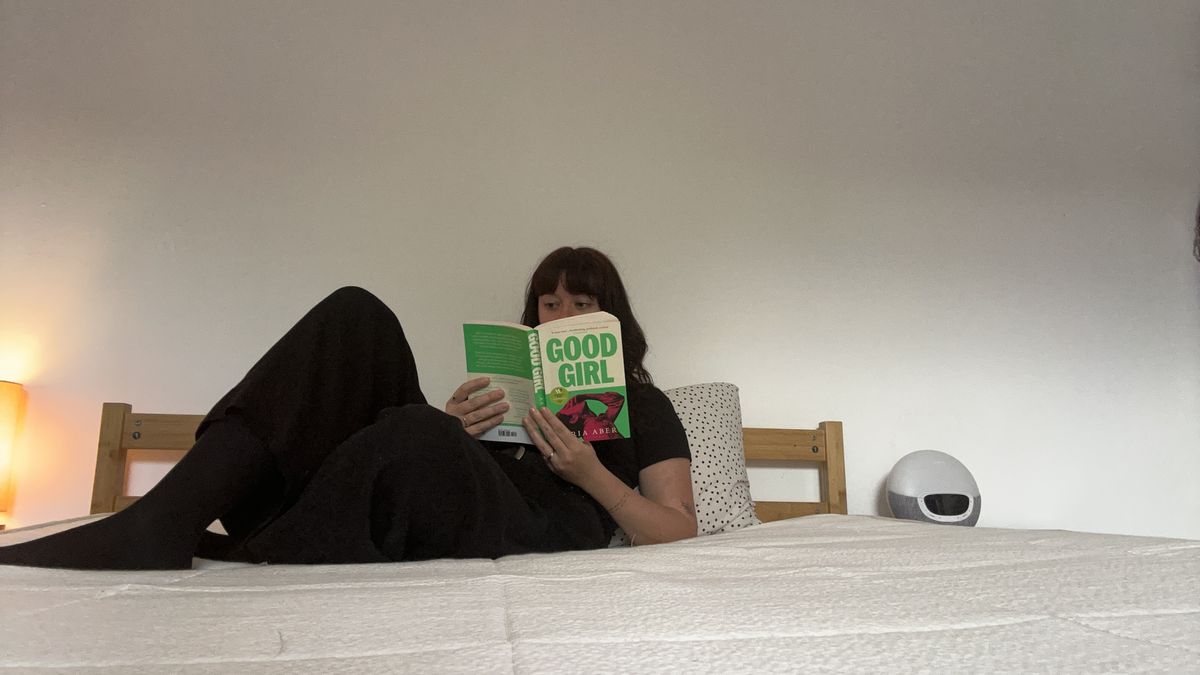 A Tom's Guide mattress tester sitting on and lying on the Awara Classic mattress