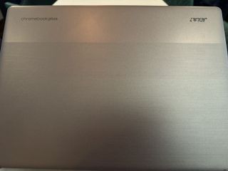 A silver Acer Chromebook Plus on a grey table