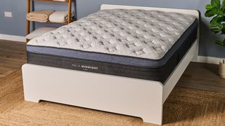 The image shows the Helix Midnight Luxe mattress on a white bed frame in a blue bedroom
