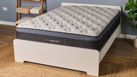 The image shows the Helix Midnight Luxe mattress on a white bed frame in a blue bedroom