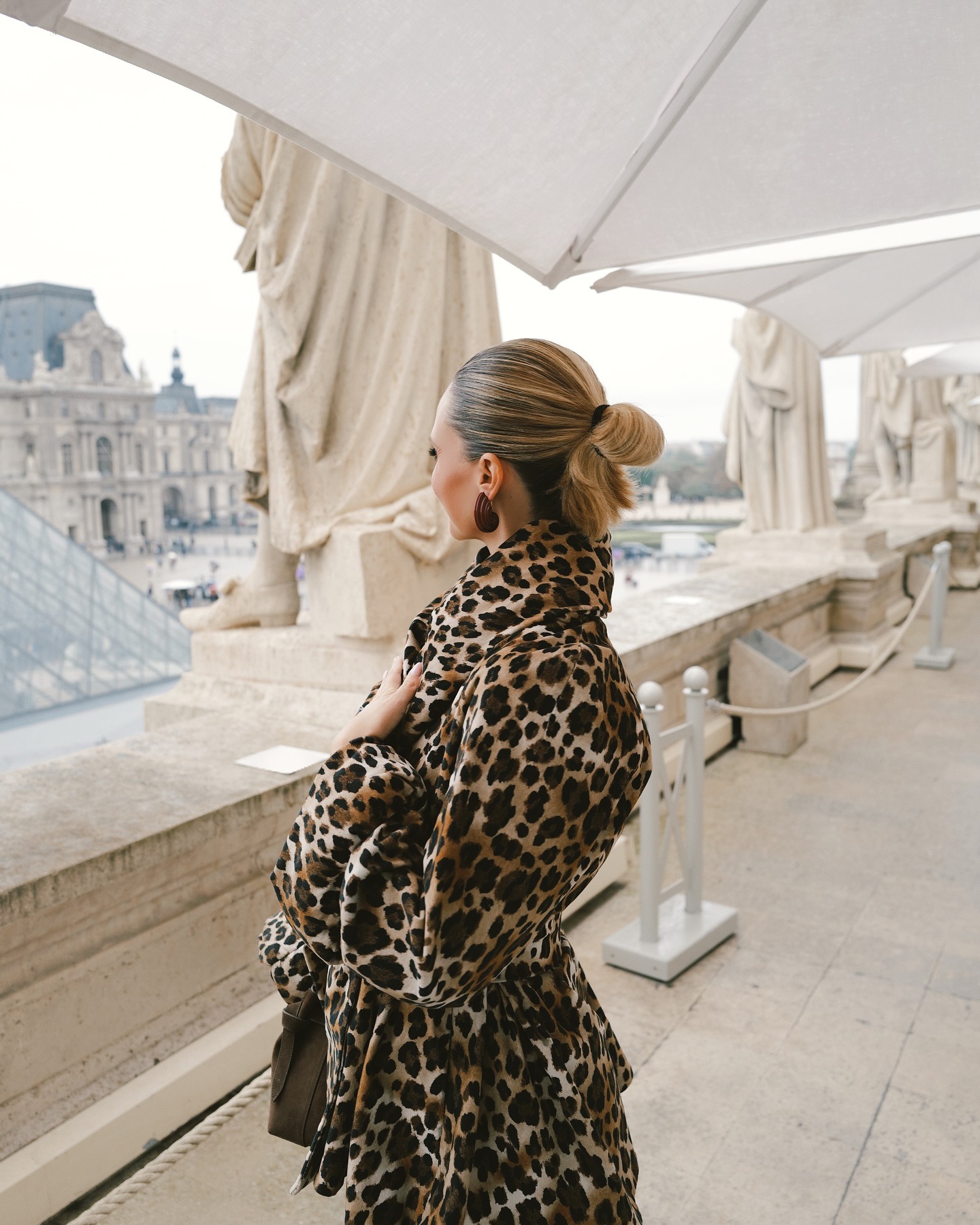Eine Frau im Louvre-Museum trägt ihr verwischtes blondes Haar zu einem Dutt hochgesteckt