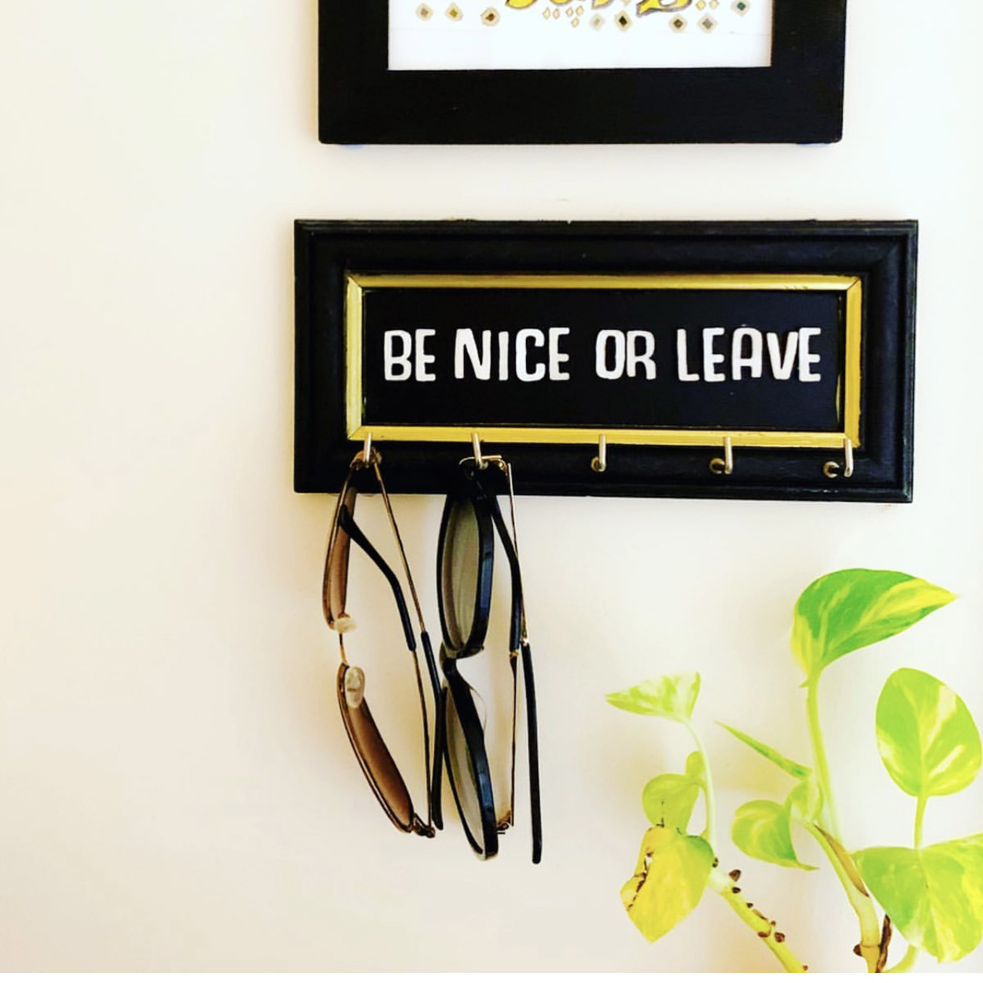 sunglasses hanging from hooks off a sign that says be nice or leave